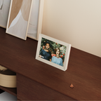 Digital photo frame displaying a couple's photo on a wooden surface.