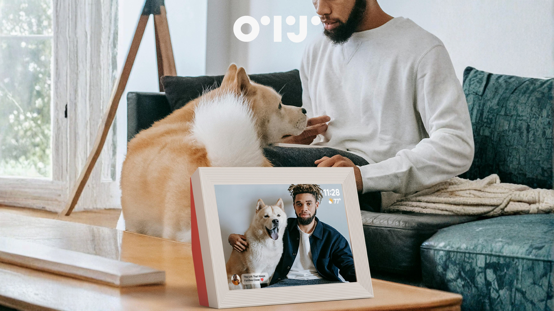 Man sitting on a couch with a dog, looking at a photo frame showing another man and a dog.