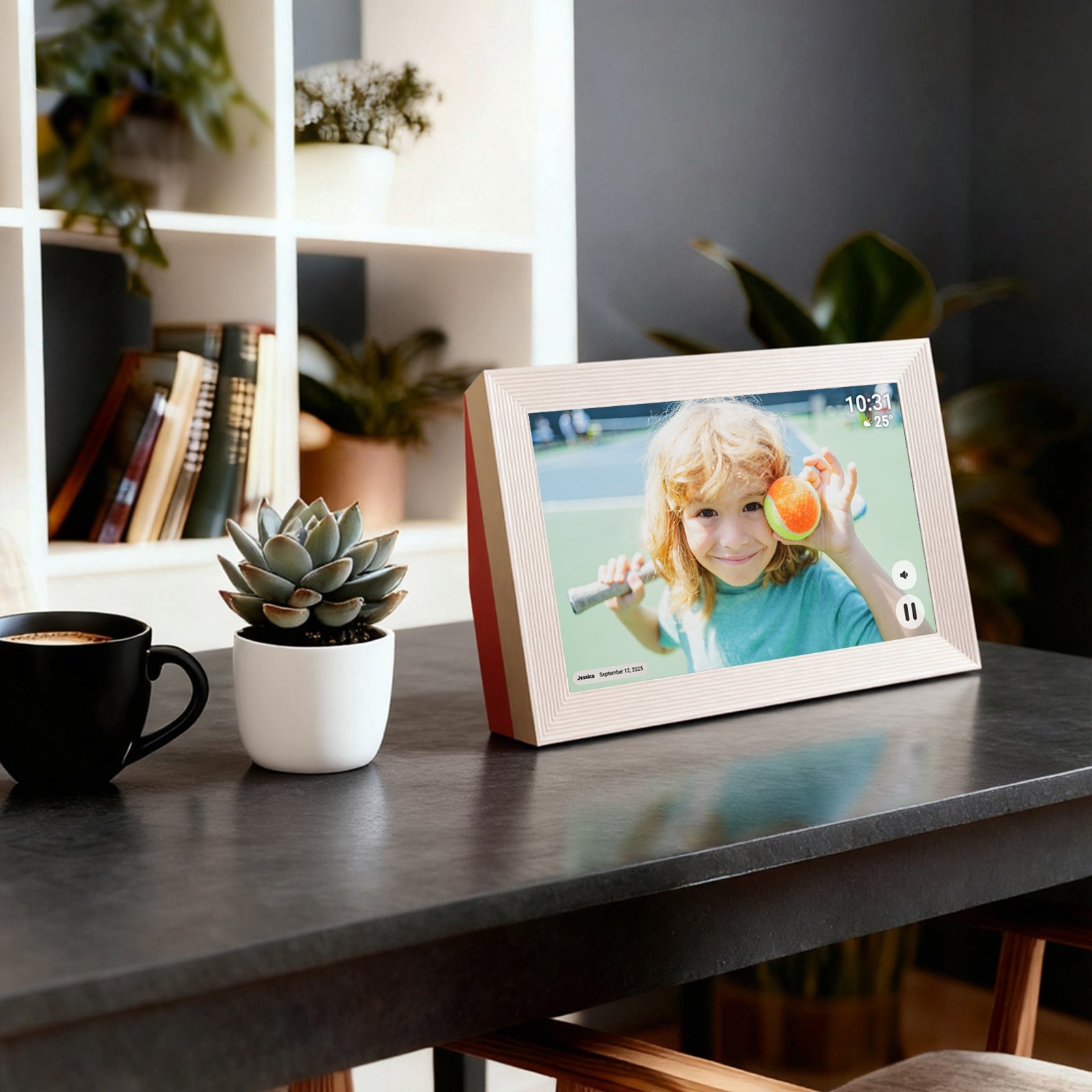Digital photo frame on a table displaying a child's picture, with a cup and plant in the background.